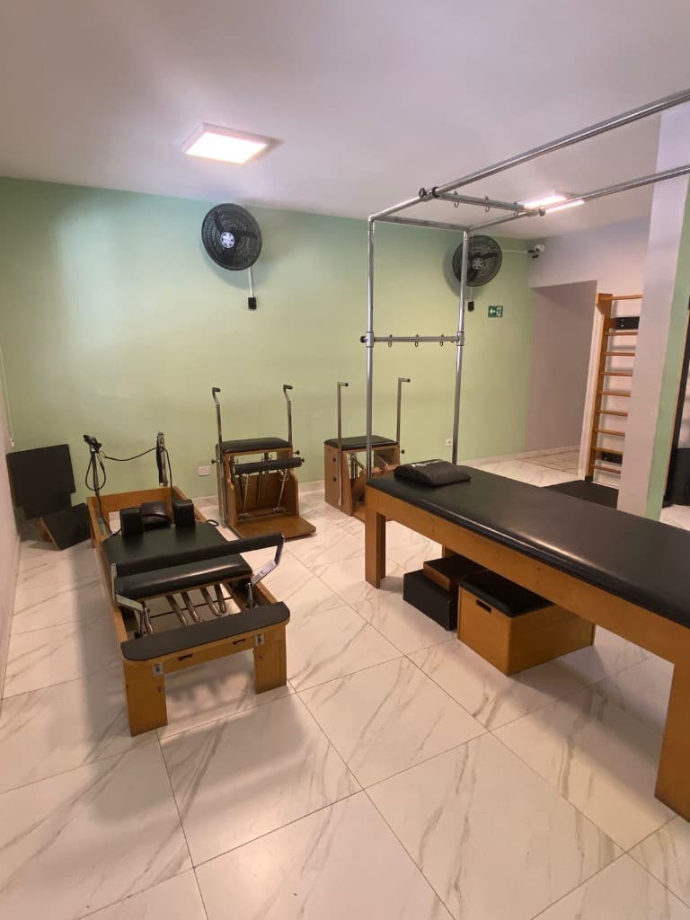 Sala de pilates com reformer, chair e aparelhos de madeira